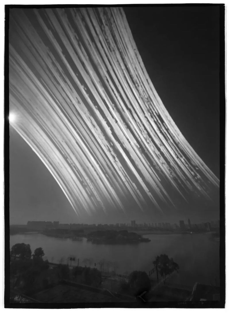 陈晓峰针孔摄影作品：编号：2022 151号；相机：墨子号；焦距：77毫米；孔径：0.33毫米直径针孔；滤镜：-3.5红镜 -3阻光镜；感光材料：上海GP3 100 12.1cmX16.5cm 黑白胶片；地点：新华小学天文台向西拍日落；时间：2022年12月18日-2024年1月4日