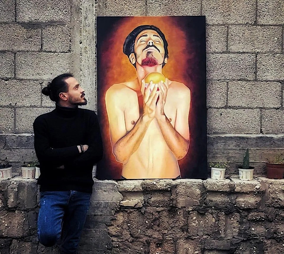 A photo from 2022 of Palestinian artist Dorgham Qreiqea with one of his figurative paintings (photo courtesy Dorgham Qreiqea’s Facebook profile)